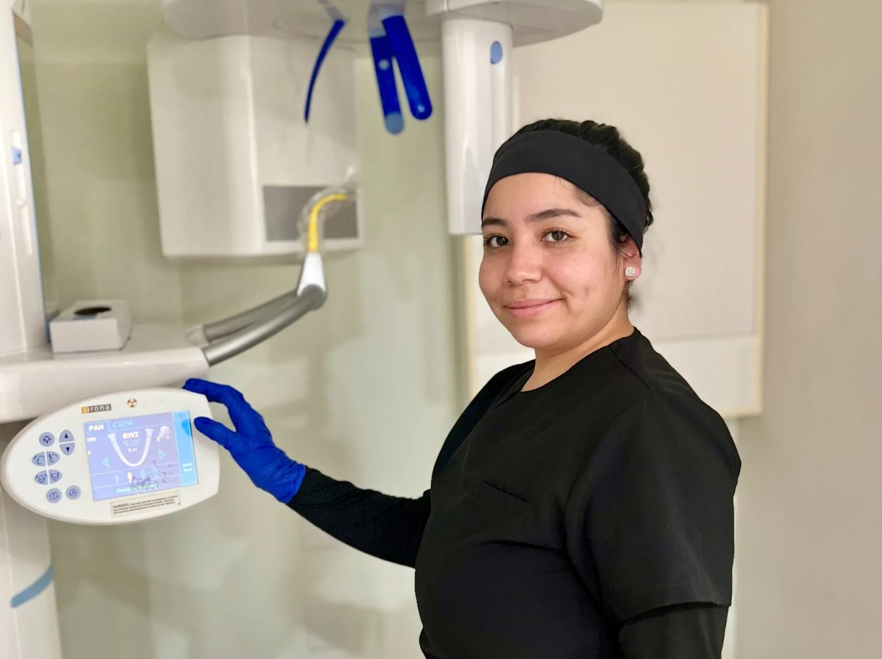Dental assistant operating orthodontic imaging equipment in a clinical setting at Apple Valley Orthodontics.