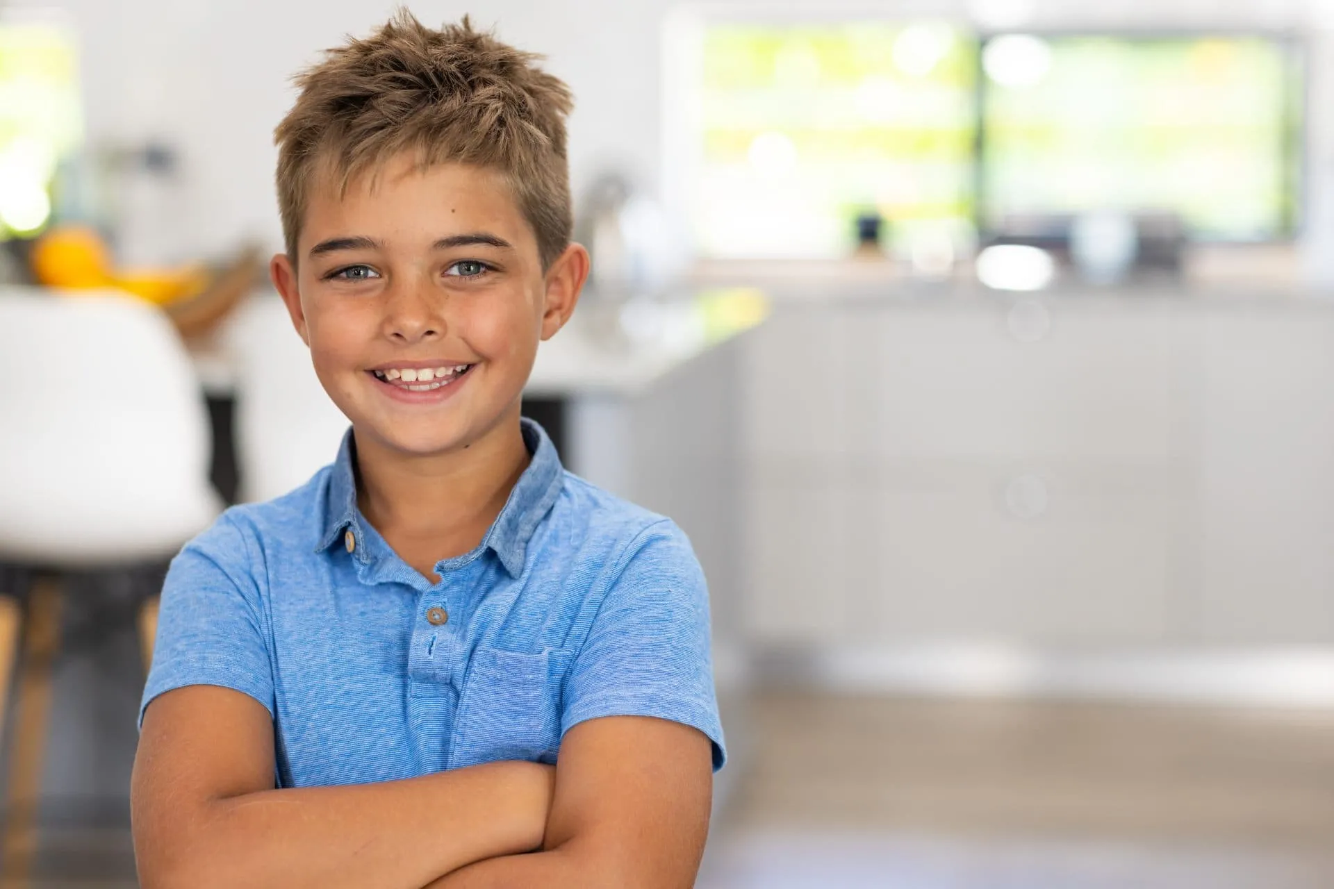 Smiling boy in a blue shirt, standing with arms crossed, representing a positive attitude towards orthodontic treatment at Apple Valley Orthodontics.